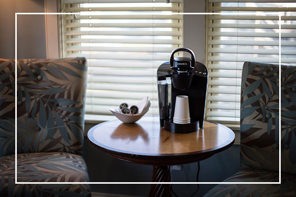 Two patterned chairs and a round table by window blinds at The Grill at Fairview Inn Restaurant.
