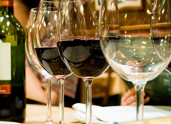 Three glasses of red wine sit beside a bottle at The Grill at Fairview Inn, Marshfield, Massachusetts.